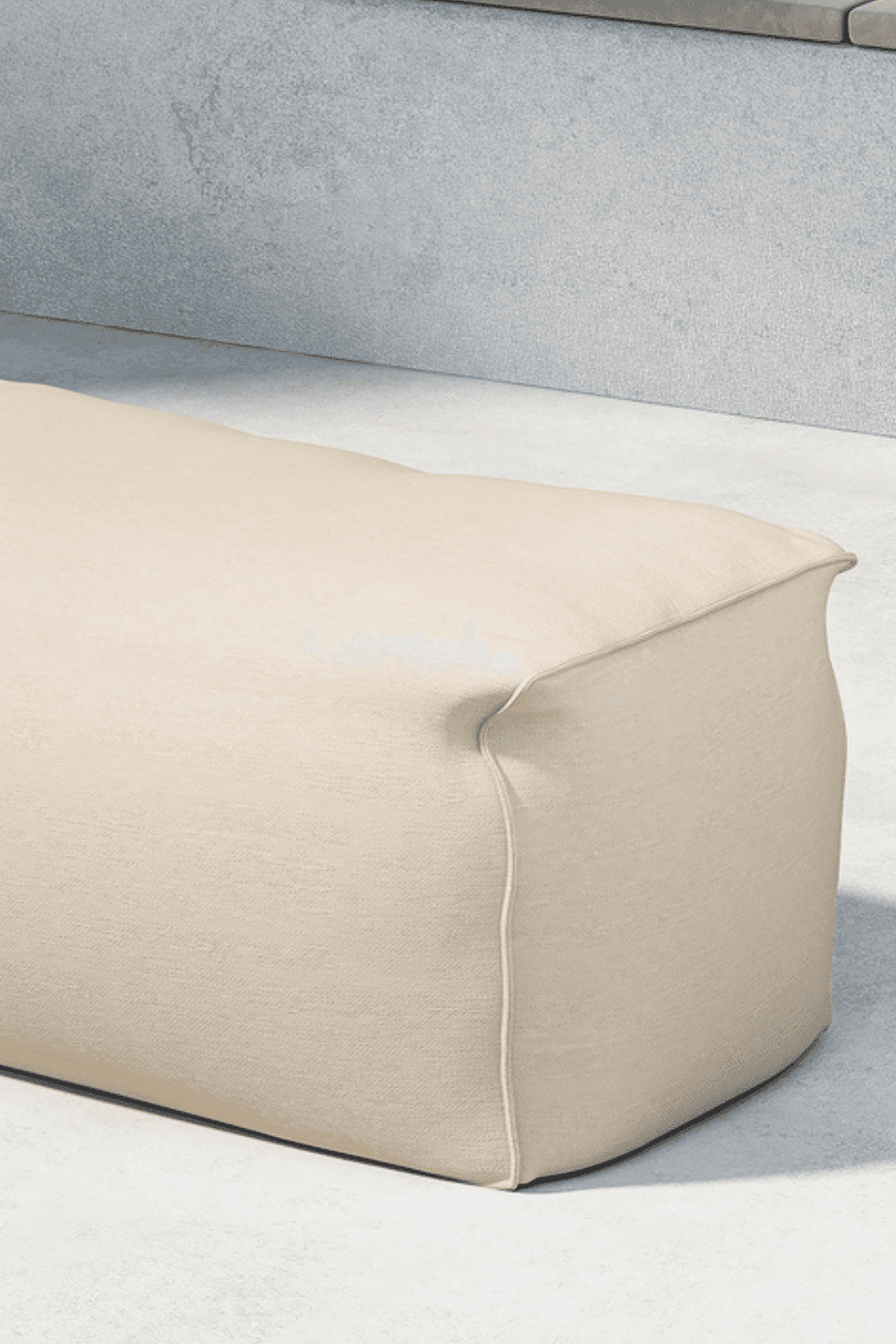 Beige rectangular outdoor pouf with a soft fabric cover, featuring clean lines and subtle stitching details, set against a concrete wall and light flooring, ideal for modern patio or indoor lounge seating. | PicSEO 1773145142544