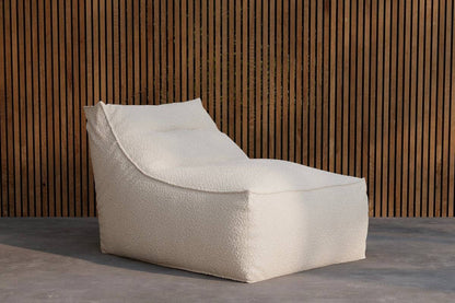Modern off-white textured chaise lounge chair with a minimalist design, set against a vertical wooden slat wall and smooth concrete flooring, ideal for contemporary indoor or outdoor relaxation spaces. | PicSEO 1773145280467