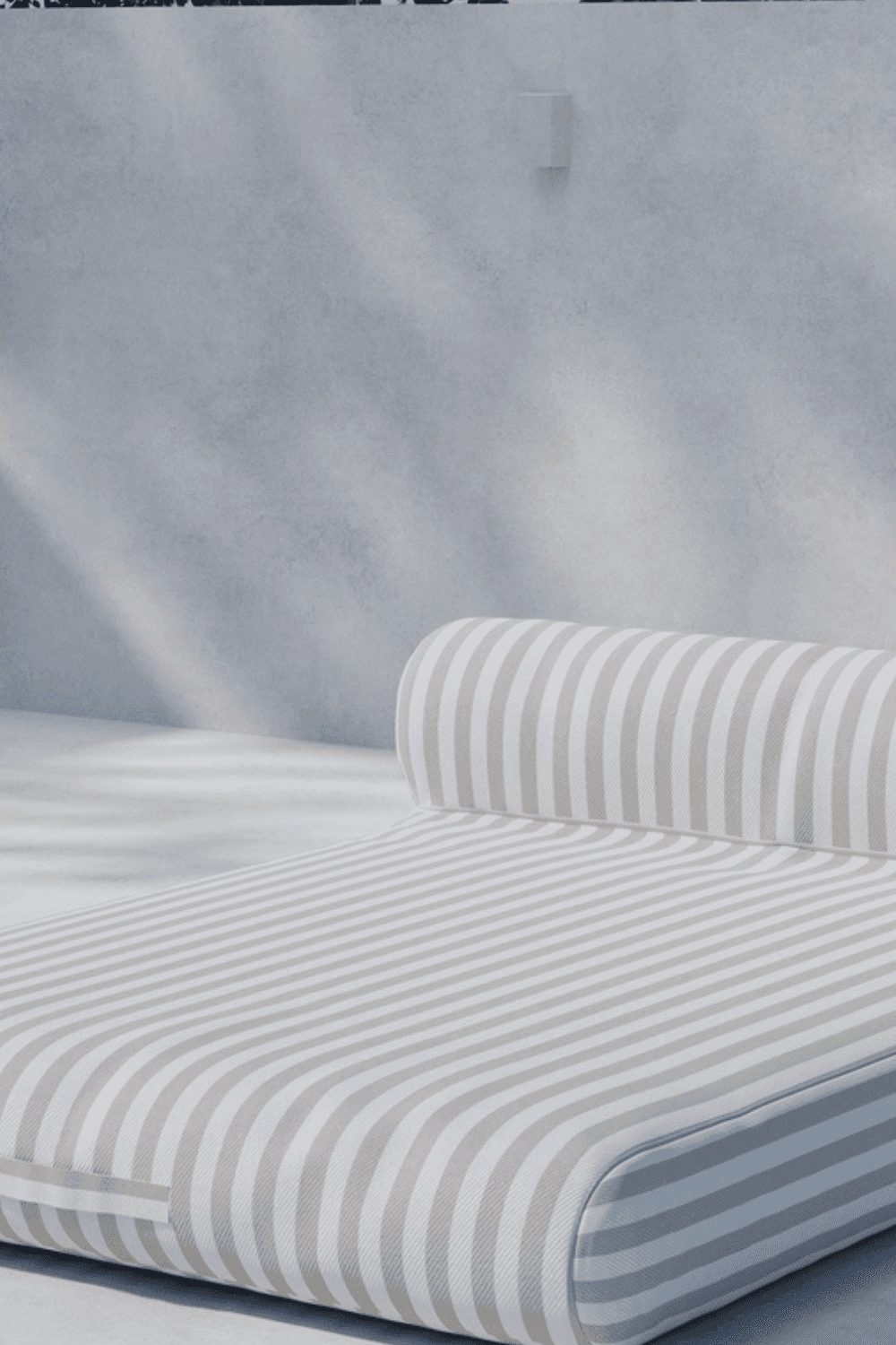 Minimalist outdoor daybed with a cushioned roll pillow, featuring light gray and white vertical stripes, set against a soft gray textured wall, perfect for modern patio or poolside relaxation. | PicSEO 1773144957744